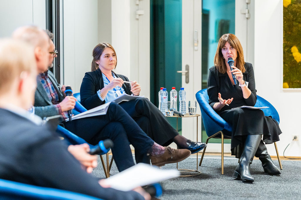 woman with a microphone on a stage addressing another speaker