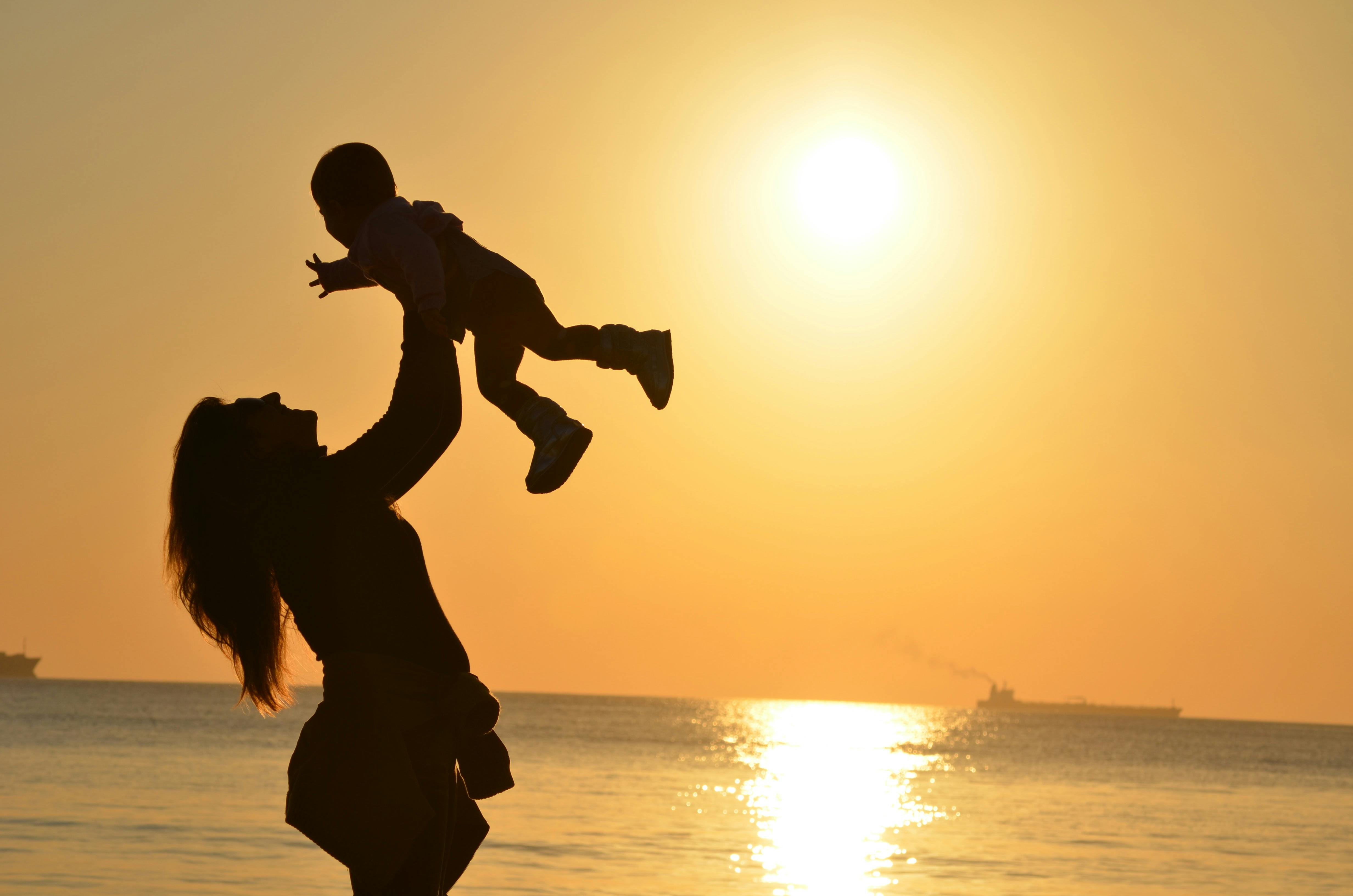 Woman holding up a baby at sunset