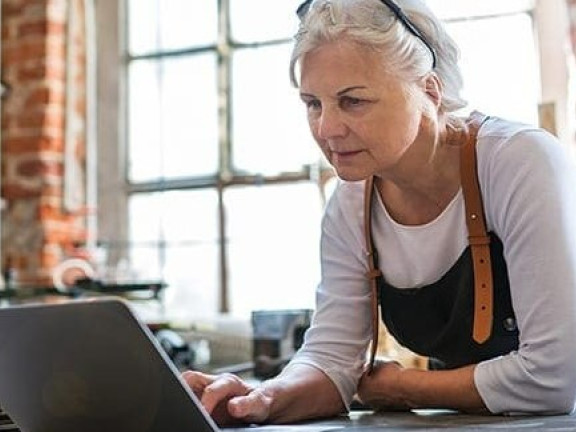 Older woman in a workshop setting, with laptop