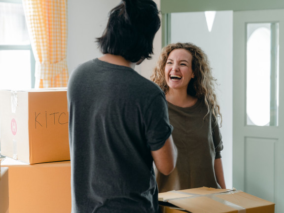 A young man and woman between moving boxes, laughing
