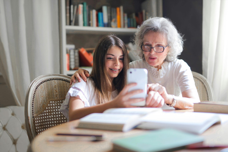 Older woman and young child look at mobile phone together