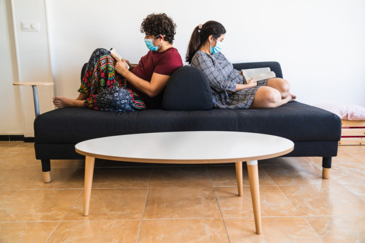 Couple sitting on couch wearing surgical masks