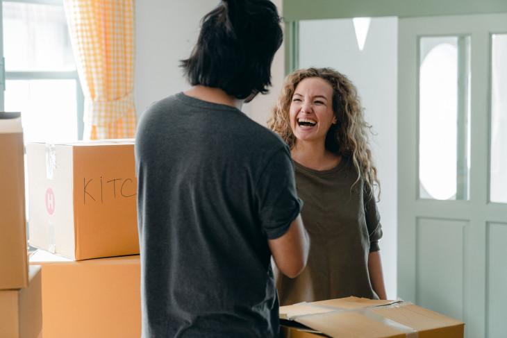 A young man and woman between moving boxes, laughing