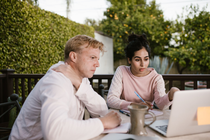 Man and woman working at at laptop in a green garden