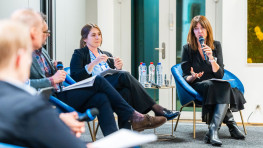 woman with a microphone on a stage addressing another speaker