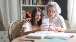 Older woman and young child look at mobile phone together