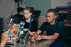 Two young people in a factory, being taught to work a specific tool