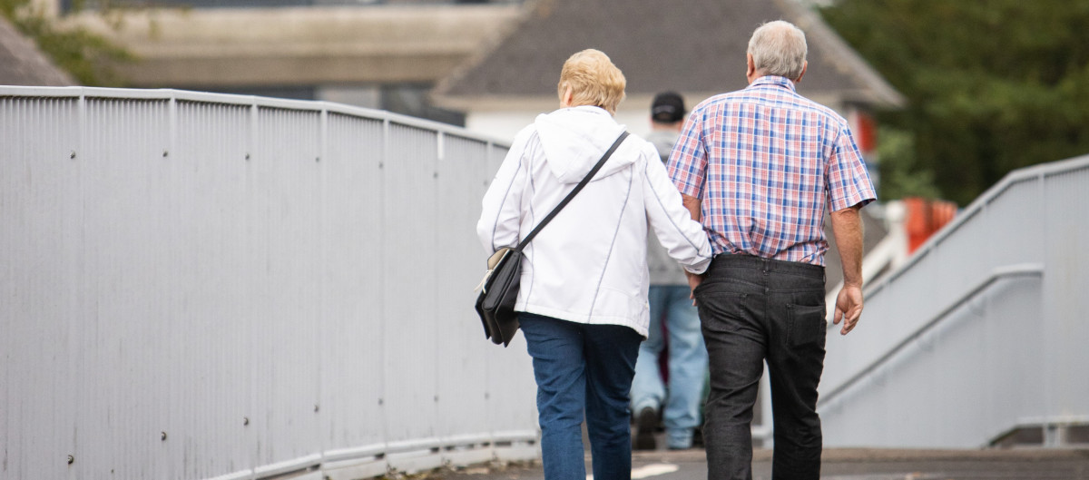 two older people walking arm in arm