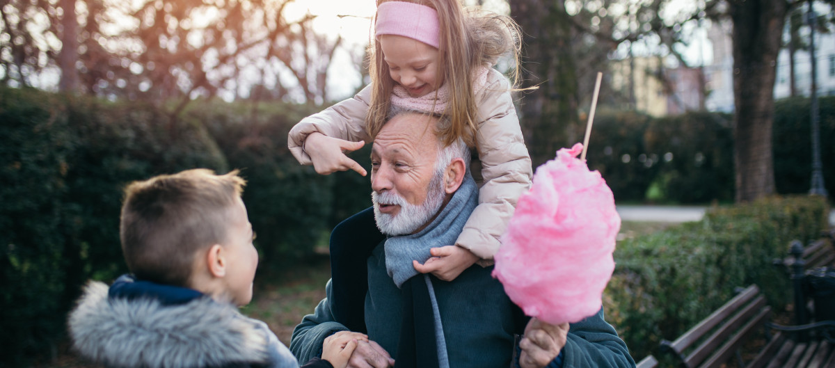 Two children playing with an older relative, he is holding pink cotton candy