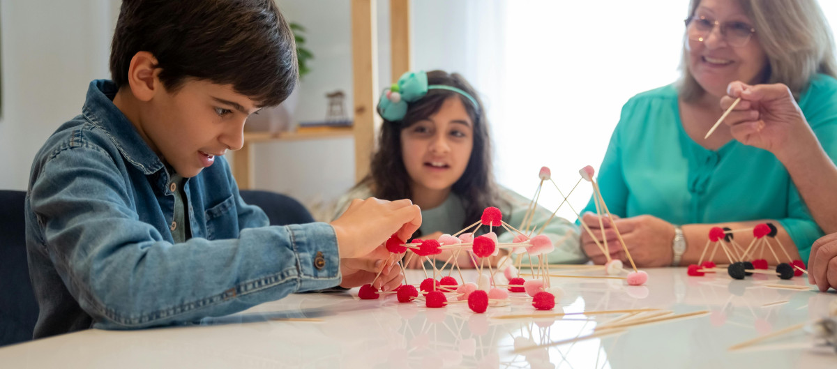 Children and older relative building a structure from toothpicks
